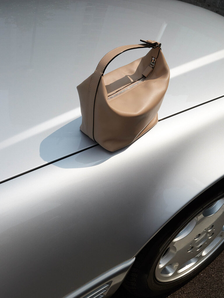 alextra mochi bag in sublime soft leather cachemire beige placed on a car