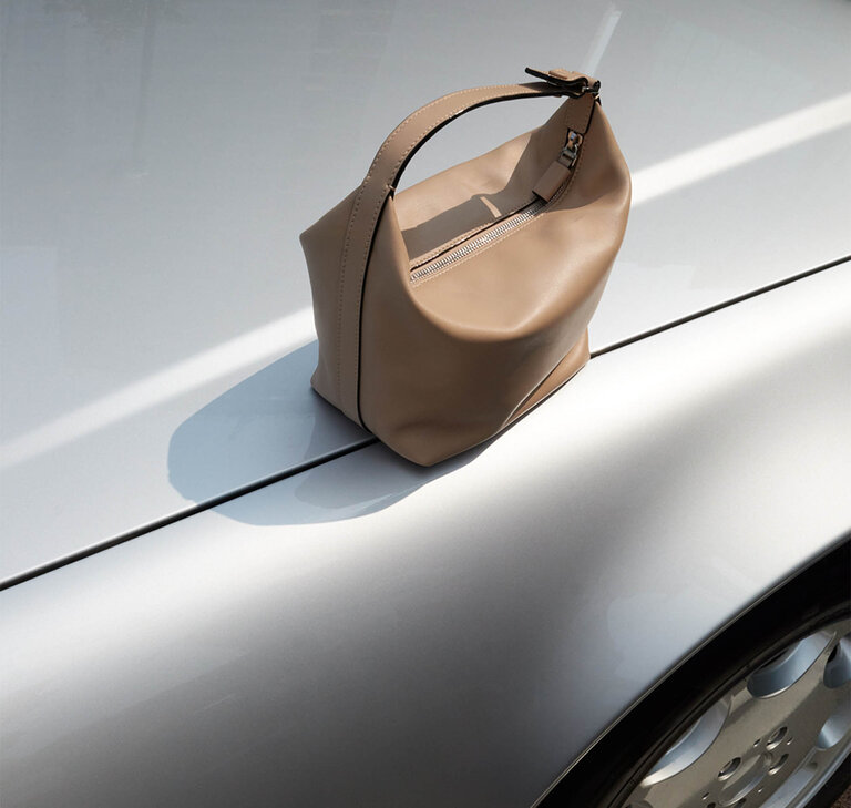 alextra mochi bag in sublime soft leather cachemire beige placed on a car